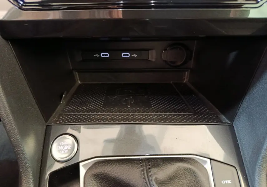 Gros plan sur la console centrale noire du Volkswagen Tiguan avec bouton start/stop et ports USB éclairés.