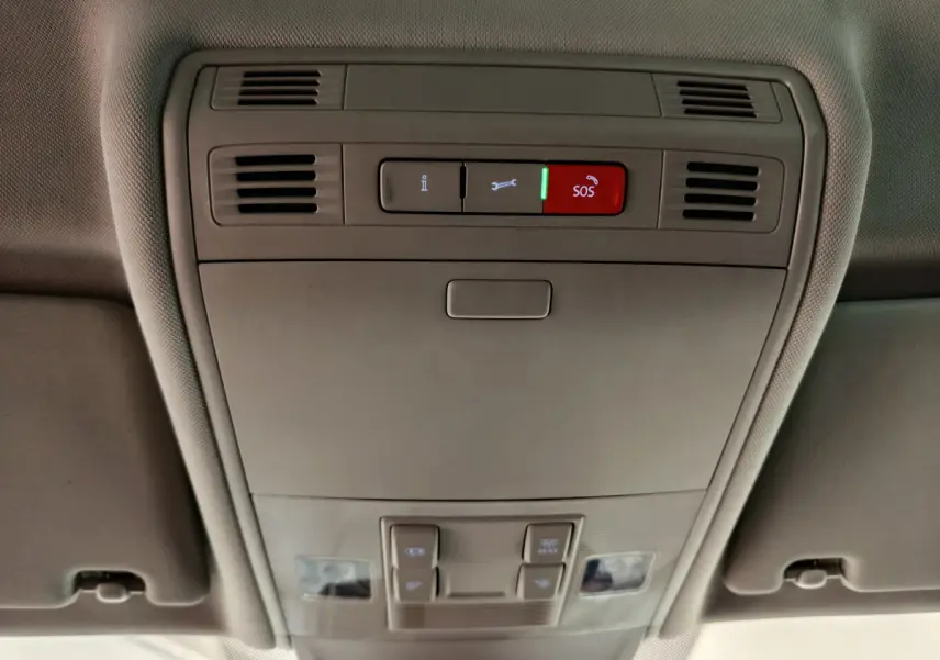 Vue en gros plan du plafonnier gris avec bouton SOS rouge et commandes d'éclairage dans un Volkswagen Tiguan 2022.