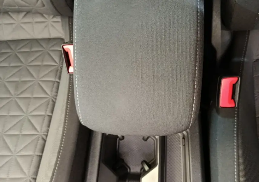 Vue plongeante sur l'accoudoir central et porte-gobelets noirs entre les sièges tissu gris du Volkswagen Tiguan hybride.