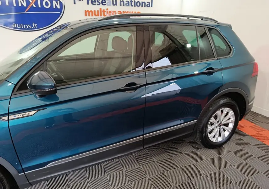 Vue latérale côté gauche du Volkswagen Tiguan bleu hybride rechargeable avec badge eHYBRID et jantes argentées.