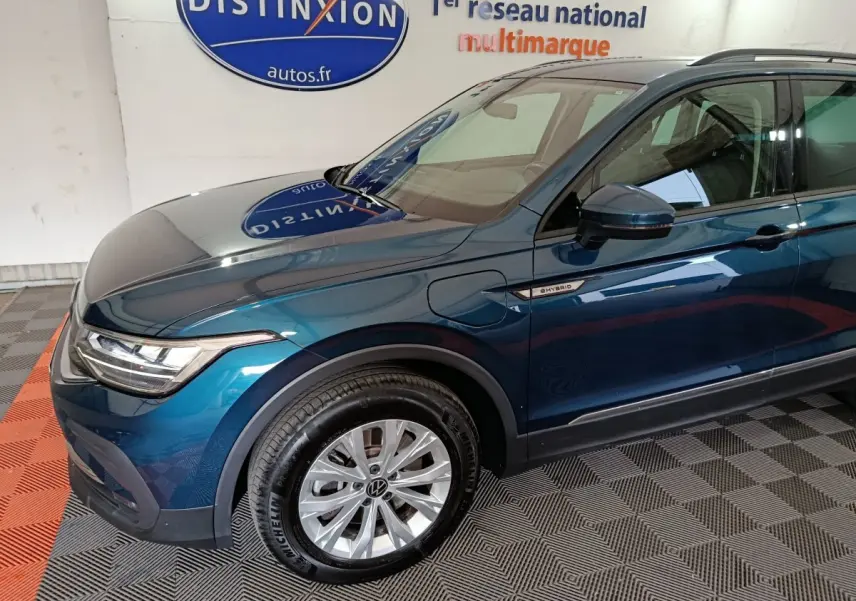Vue 3/4 avant droit d'un Volkswagen Tiguan bleu hybride rechargeable avec badge "eHybrid" sur aile avant.