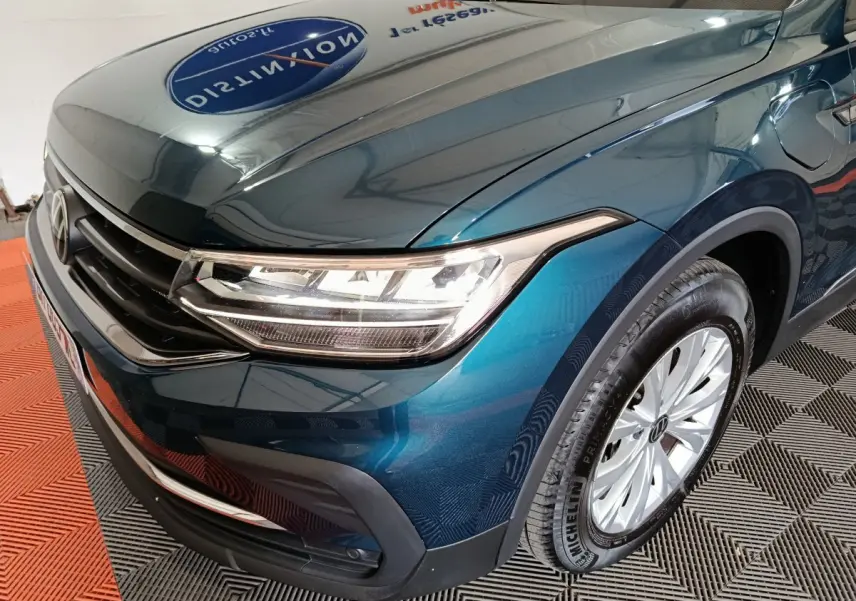 Vue 3/4 avant droit d'un Volkswagen Tiguan bleu avec phares LED et jantes alliage visibles.
