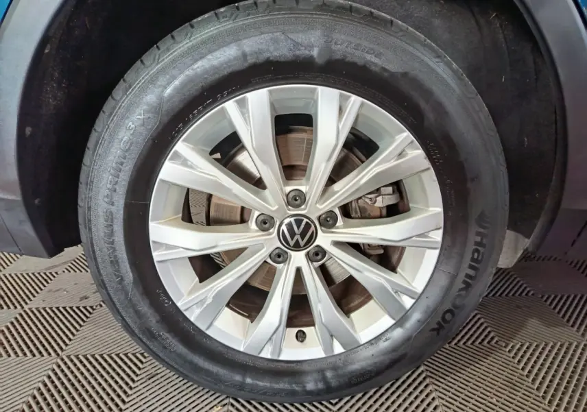 Gros plan sur la jante alliage argentée avec logo Volkswagen d’un Volkswagen Tiguan bleu hybride rechargeable.