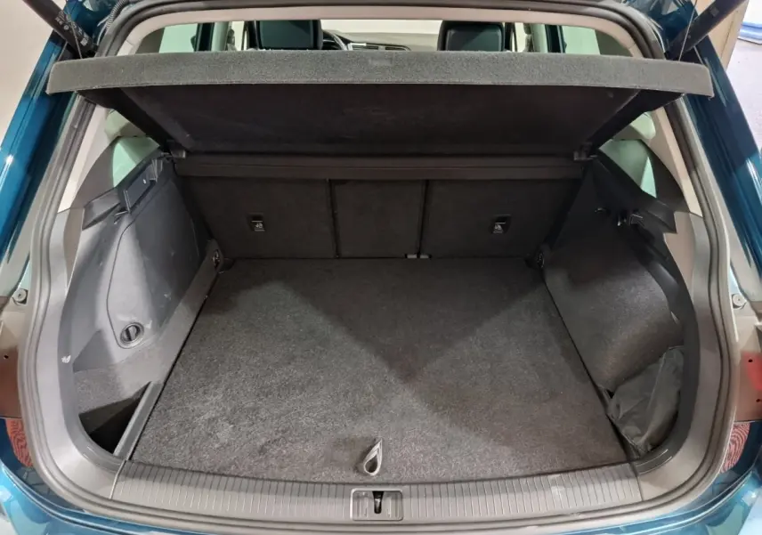 Coffre ouvert en bleu du Volkswagen Tiguan 1.4 eHybrid 245 DSG6, vue arrière montrant l'espace de chargement vide.