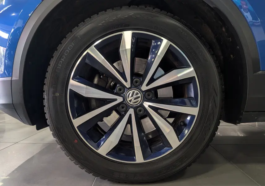 Gros plan sur la jante bi-ton bleu et argent du Volkswagen T-Roc bleu Ravenna avec toit blanc, côté gauche.