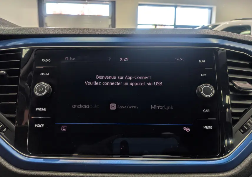 Écran central tactile du Volkswagen T-Roc bleu Ravenna avec interface App-Connect et commandes autour.