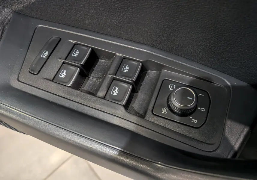 Panneau de commandes des vitres et rétroviseurs électriques côté conducteur du Volkswagen T-Roc bleu Ravenna toit blanc.