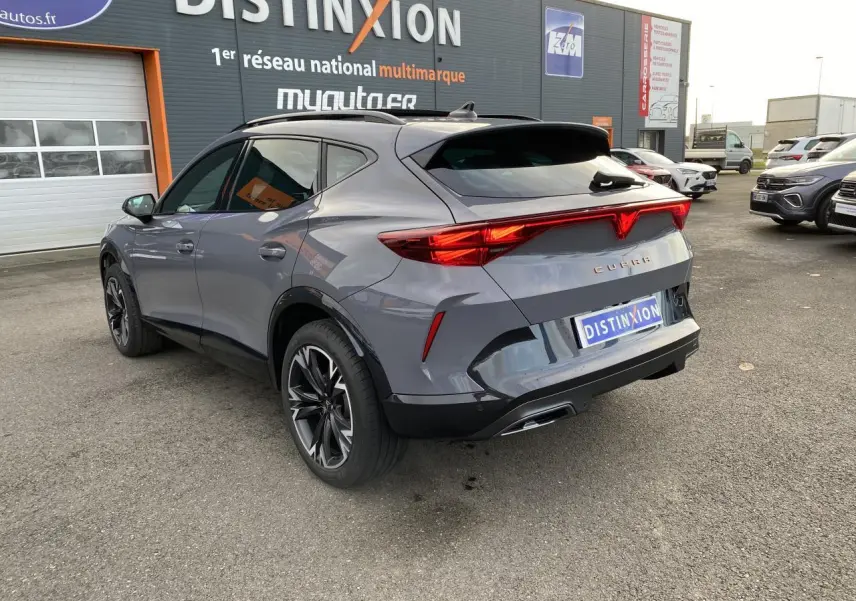 Vue 3/4 arrière droit d'un CUPRA Formentor gris Graphène avec feux arrière allumés et jantes noires sport.