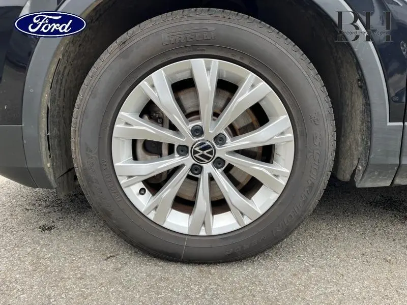 Gros plan sur la roue avant droite du Volkswagen Tiguan noir intense nacrée avec jante alu à multiples branches.