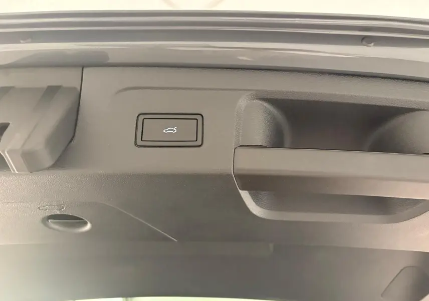Bouton d'ouverture électrique du hayon sur la partie intérieure du coffre d'un Volkswagen Touran gris dauphin 2025.