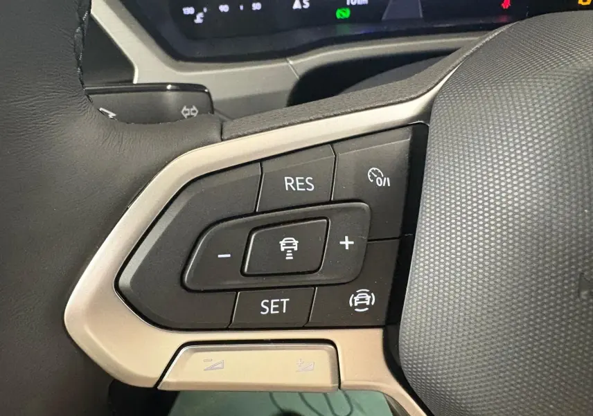 Gros plan sur les commandes de régulateur de vitesse au volant du Volkswagen Touran gris dauphin 2025.
