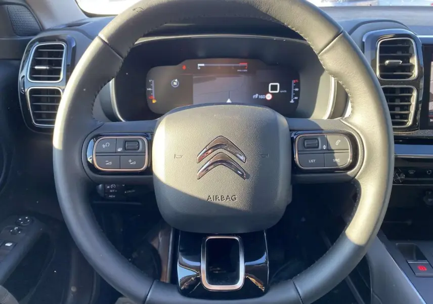 Vue rapprochée du volant en cuir noir du Citroën C5 Aircross 2021 avec commandes intégrées et tableau de bord numérique.