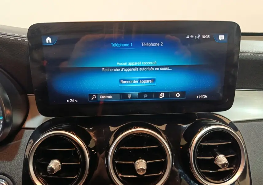 Écran tactile central et trois aérateurs ronds chromés du tableau de bord du Mercedes GLC bleu, vue intérieure frontale.