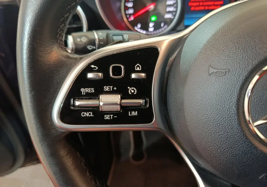 Gros plan sur les commandes de régulateur de vitesse au volant cuir d'une Mercedes GLC hybride rechargeable 2021.