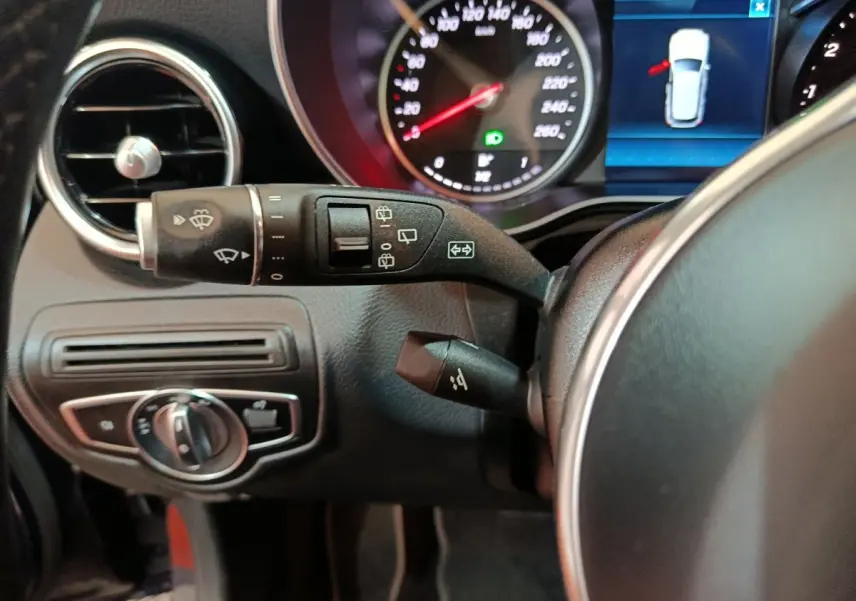 Gros plan sur la colonne de direction et le tableau de bord du Mercedes GLC bleu, avec commandes essuie-glaces et affichage digital.