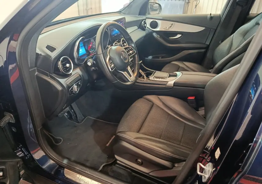 Intérieur côté conducteur d'un Mercedes GLC 300 E Business Line 2021 bleu, avec tableau de bord digital et sièges cuir noirs.