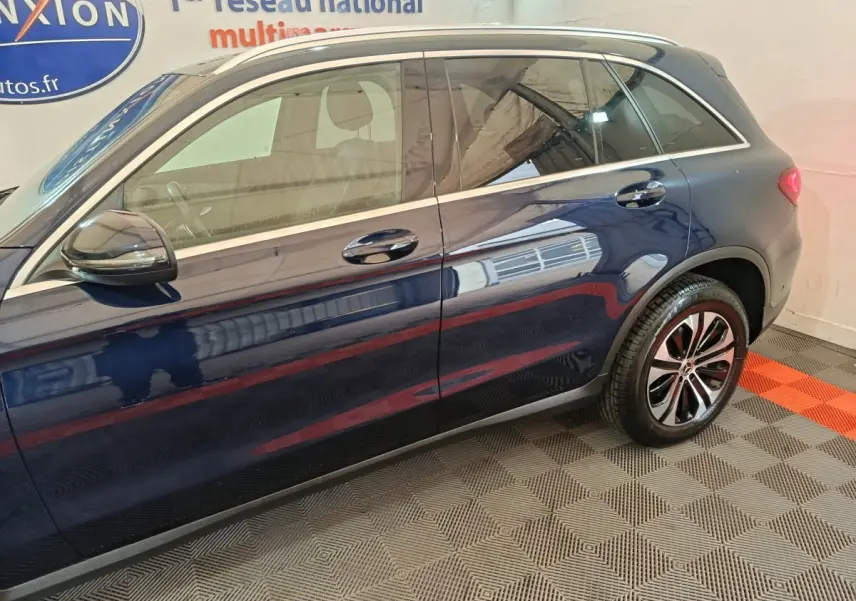 Vue latérale côté gauche d'un Mercedes GLC 300 E Business Line bleu avec jantes alliage et toit chromé.