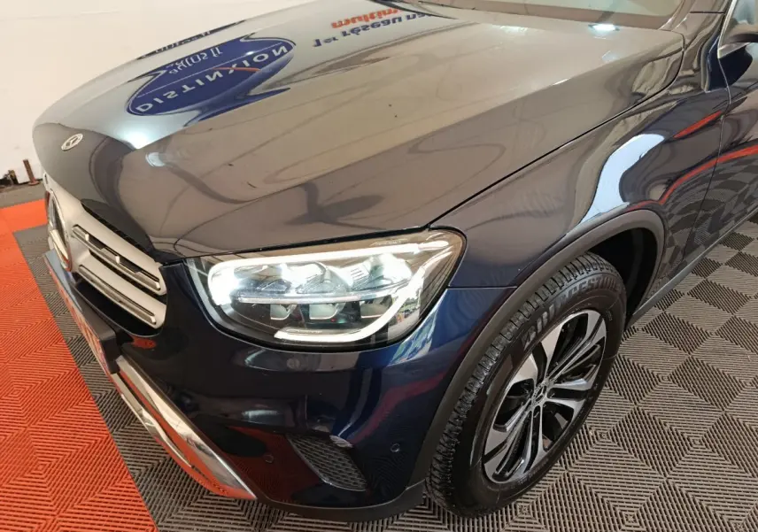 Vue 3/4 avant droit d'un Mercedes GLC 300 E Business Line bleu avec phares LED allumés et jantes alliage.