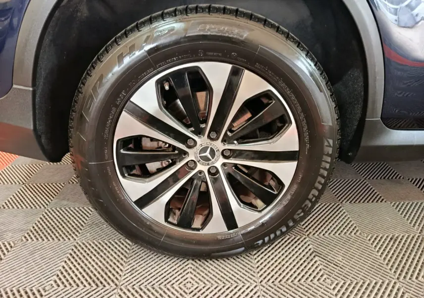 Gros plan sur la roue avant droite du Mercedes GLC bleu 2021 avec jante alliage bicolore et pneu Bridgestone.