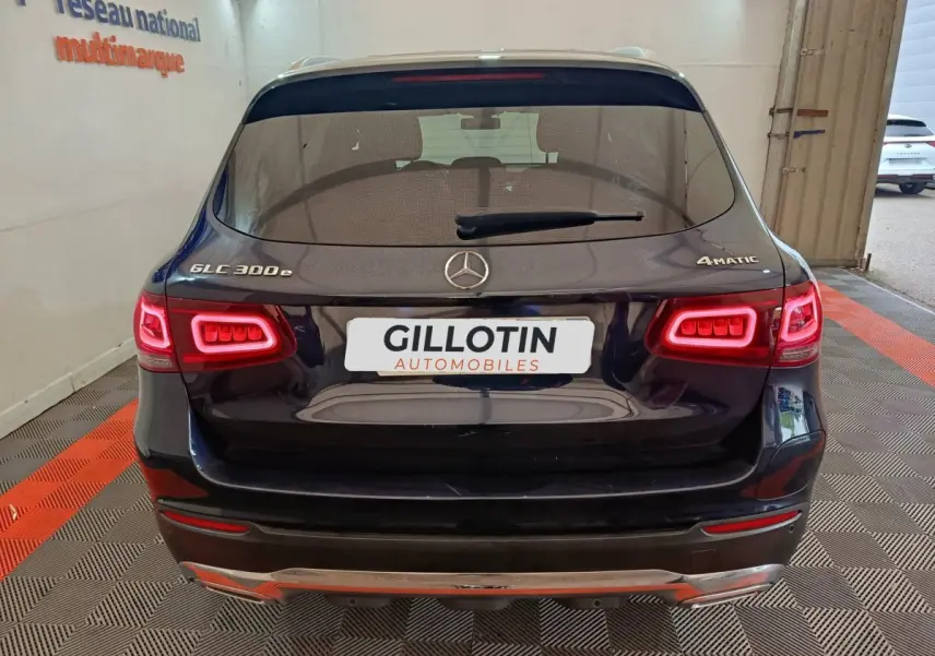 Vue arrière d'un Mercedes GLC 300e 4MATIC bleu avec feux LED allumés dans un showroom.