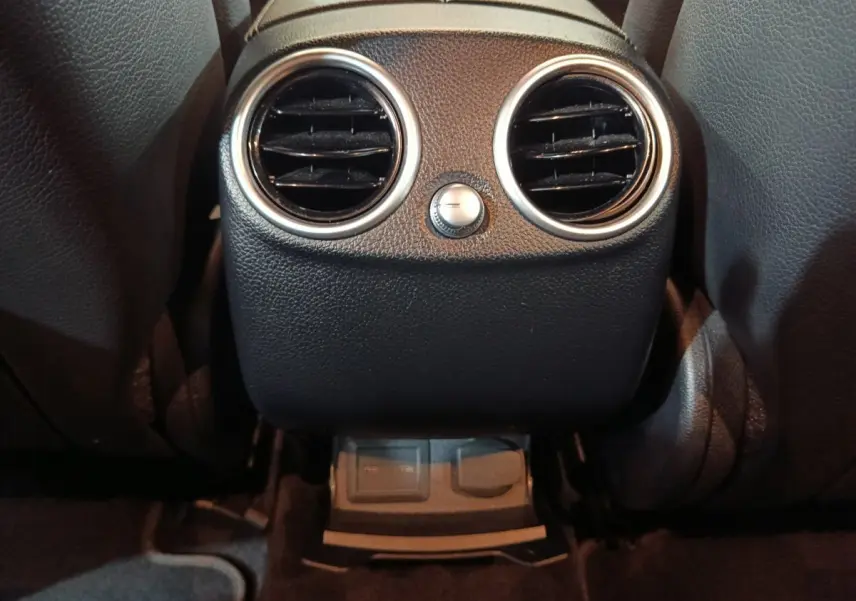 Détail des aérateurs arrière noirs avec bord chromé et commandes de ventilation dans un Mercedes GLC 300 E bleu.