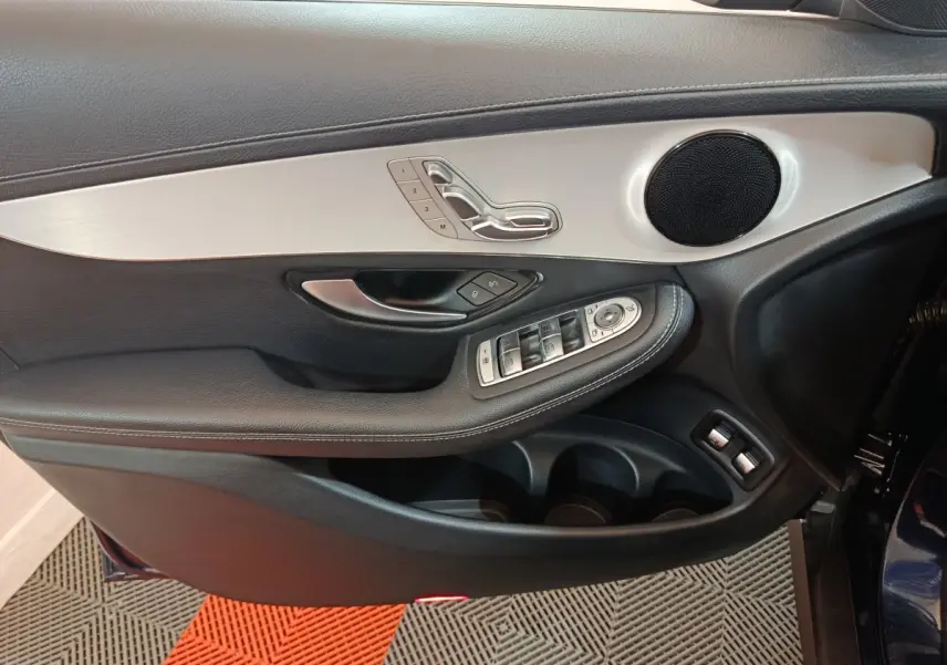 Gros plan sur la porte côté gauche du Mercedes GLC bleu, montrant les commandes de siège et les boutons de fenêtre.