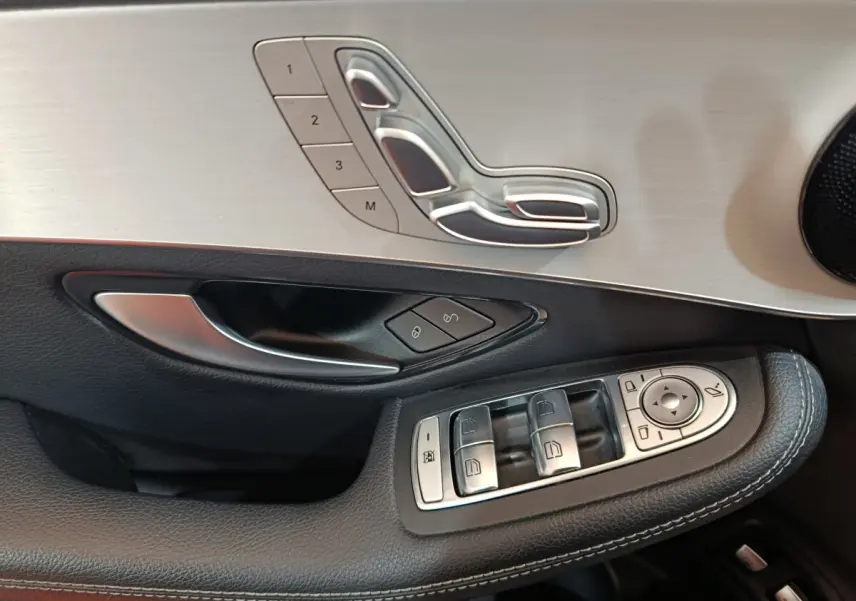 Gros plan sur la porte côté gauche du Mercedes GLC bleu, avec commandes de sièges et vitres en aluminium brossé.