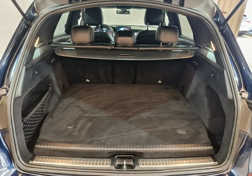 Coffre ouvert d'un Mercedes GLC 300 E bleu, vue arrière montrant l'espace de chargement et la banquette arrière.
