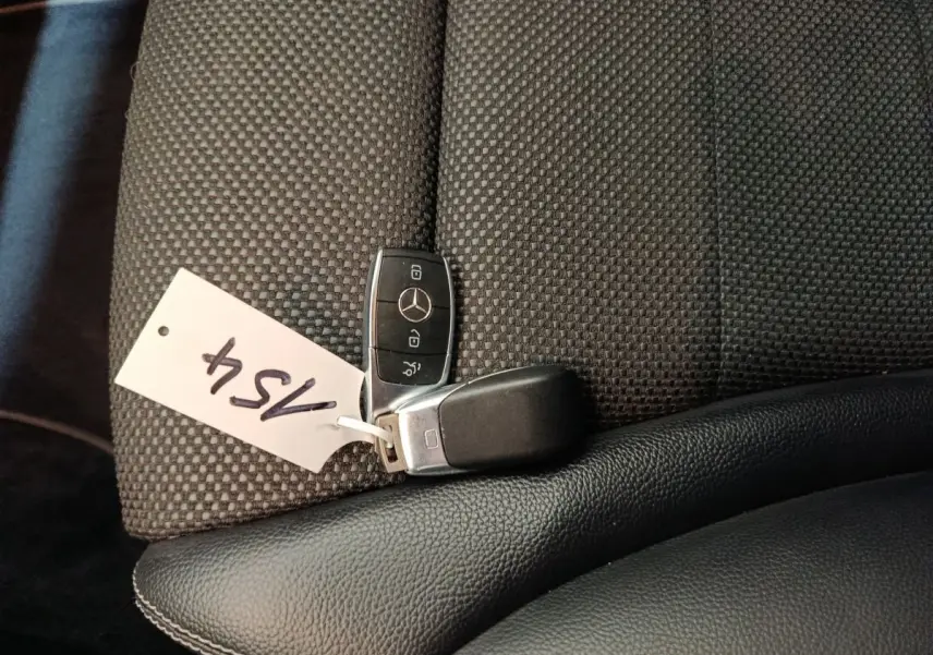 Clé Mercedes posée sur un siège tissu gris foncé avec appui-coude en cuir noir dans un GLC 300 E Business Line 2021.