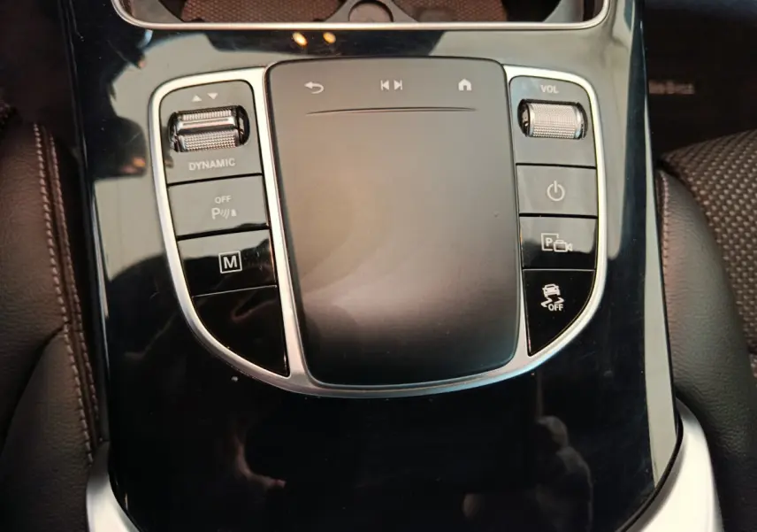 Gros plan sur la console centrale noire brillante avec pavé tactile et commandes du Mercedes GLC 300 E bleu hybride rechargeable.