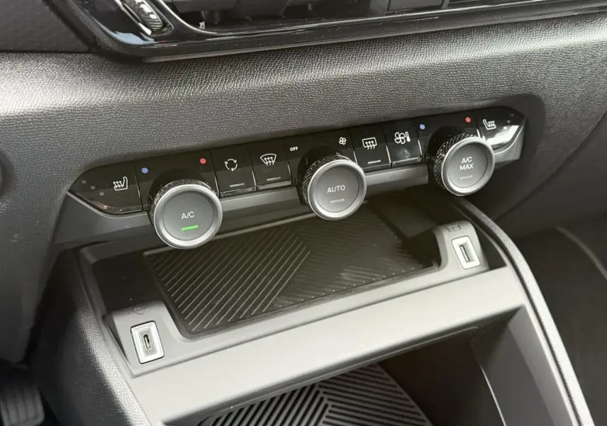 Gros plan sur la console centrale noire de la Citroën C4 avec commandes climatisation et ports USB visibles