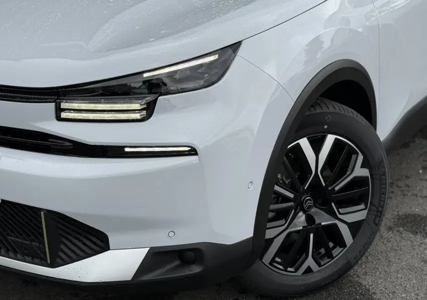 Gros plan sur l'avant droit blanc Okénite du Citroën C4 NV Hybrid 145 avec feux LED et jante alliage 18 pouces.