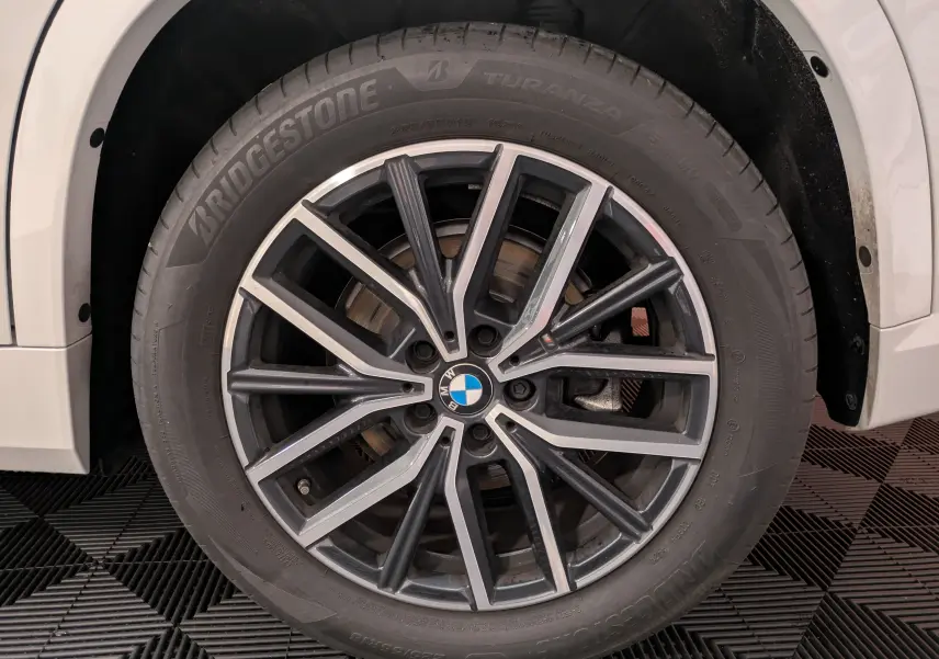 Gros plan sur la jante avant droite bicolore 18 pouces M d’un BMW X1 blanc 2025 avec pneu Bridgestone.