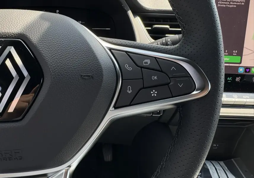 Gros plan sur le volant cuir multifonctions du Renault Captur gris Cassiopée avec commandes intégrées et écran tactile visible.