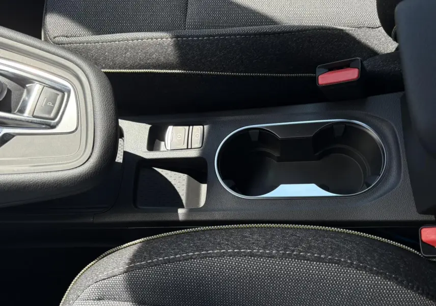 Gros plan sur la console centrale du Renault Captur gris Cassiopée, avec porte-gobelets et commandes de frein électrique.