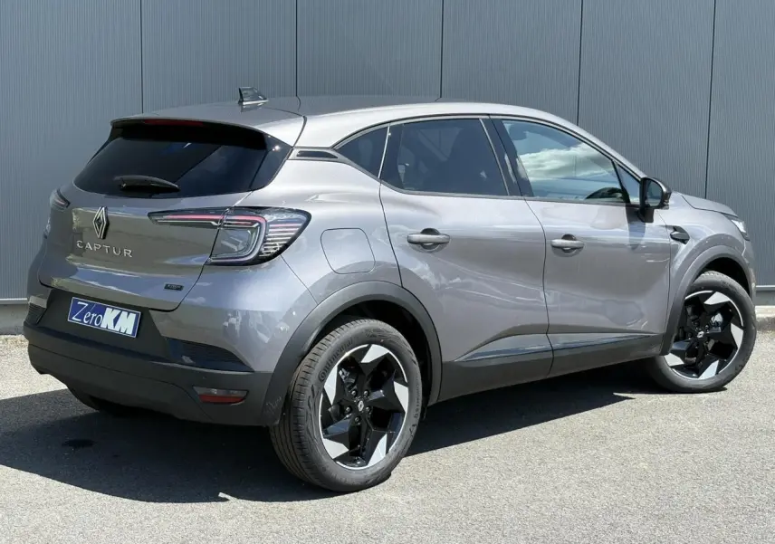 Renault Captur gris Cassiopée en 3/4 arrière droit, jantes noires et feux arrière LED distinctifs visibles.