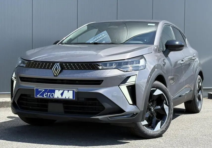 Renault Captur gris Cassiopée en 3/4 avant droit, avec calandre noire et jantes aluminium 18 pouces noires et argentées.