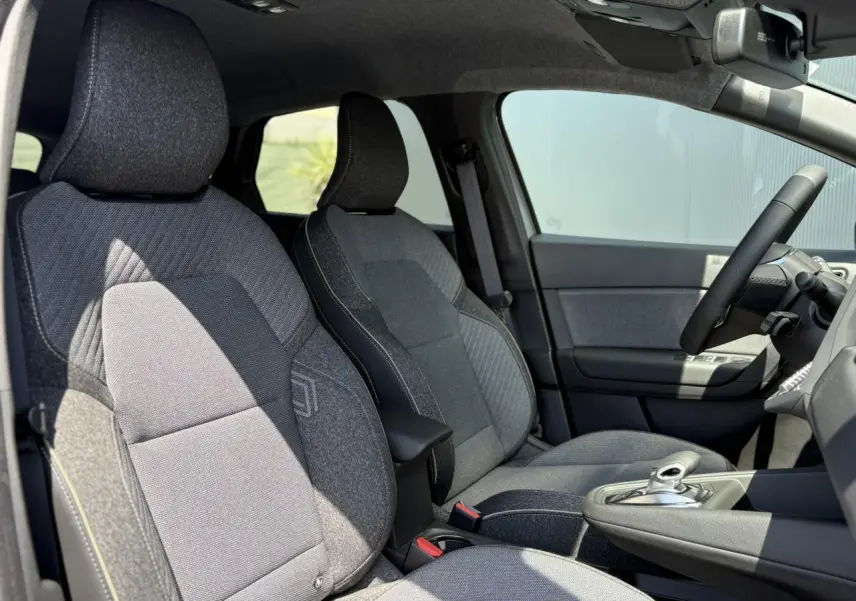 Vue intérieure côté conducteur du Renault Captur 2025 gris Cassiopée, sièges tissu gris et volant cuir multifonctions.