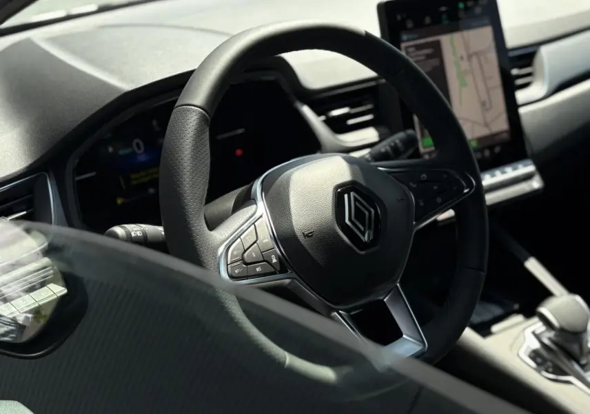 Gros plan sur le volant cuir multifonctions Renault Captur 2025 avec tableau de bord et écran tactile visible en arrière-plan.