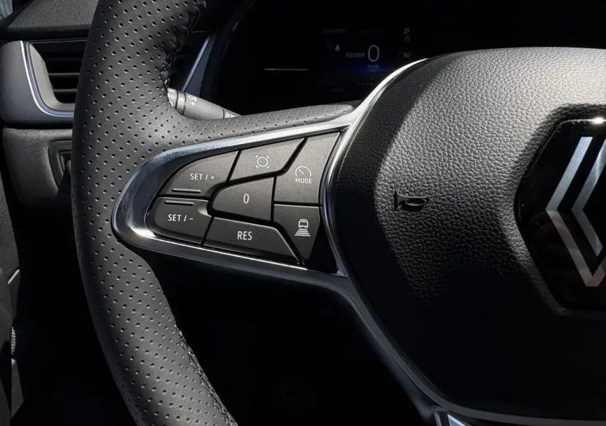 Gros plan sur le volant cuir multifonctions du Renault Captur 2025, avec commandes du régulateur adaptatif visibles.
