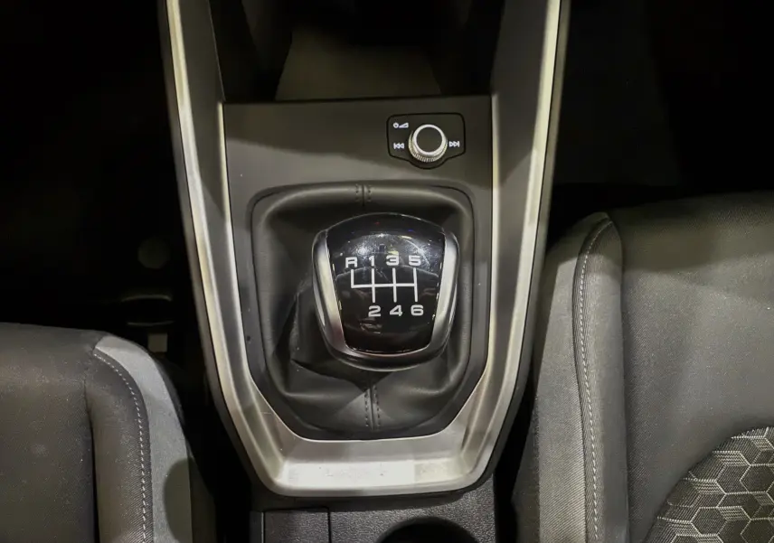 Le levier de vitesses manuel 6 rapports de l'Audi A1 30 TFSI S-Line 2024, entouré de sièges en tissu noir.