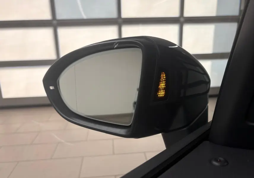 Rétroviseur extérieur droit du Volkswagen Touran gris Dauphin 2025 avec clignotant orange allumé.