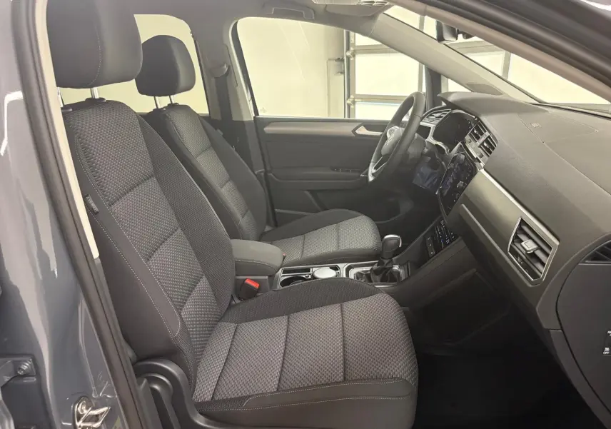 Intérieur du Volkswagen Touran 2025 gris dauphin, vue côté gauche sur les sièges avant et tableau de bord moderne.