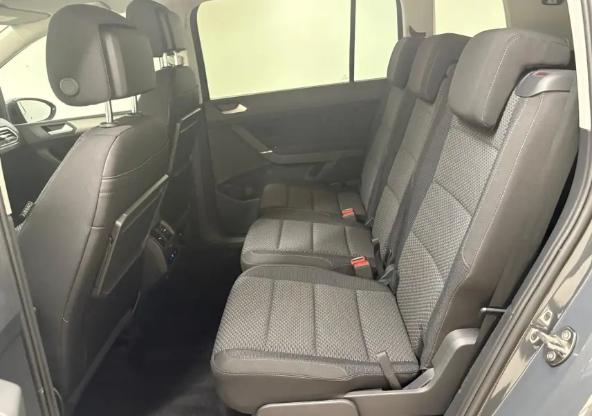 Vue latérale intérieure des sièges arrière gris foncé du Volkswagen Touran 2025, version 7 places avec finition VW Edition.
