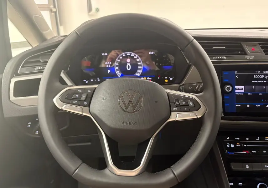 Vue rapprochée du volant multifonction noir du Volkswagen Touran 2025 avec tableau de bord numérique et écran tactile central.