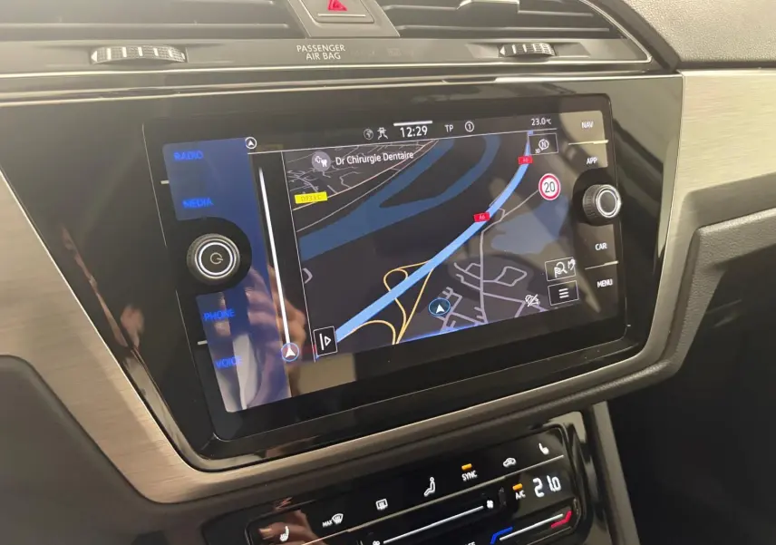 Écran tactile de navigation du Volkswagen Touran gris dauphin 2025 avec commandes climatisation et interface moderne.