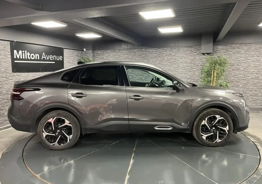 Profil côté droit d'une Citroën C4 2024 gris métallisé avec jantes alliage 18'' et lignes fluides modernes.