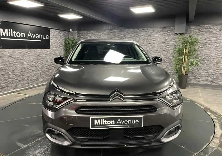 Vue frontale d'une Citroën C4 gris métallisé 2024 avec calandre distinctive et phares LED en showroom.