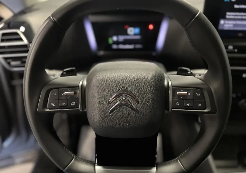 Volant cuir noir de Citroën C4 2024 avec commandes intégrées et logo double chevron au centre.