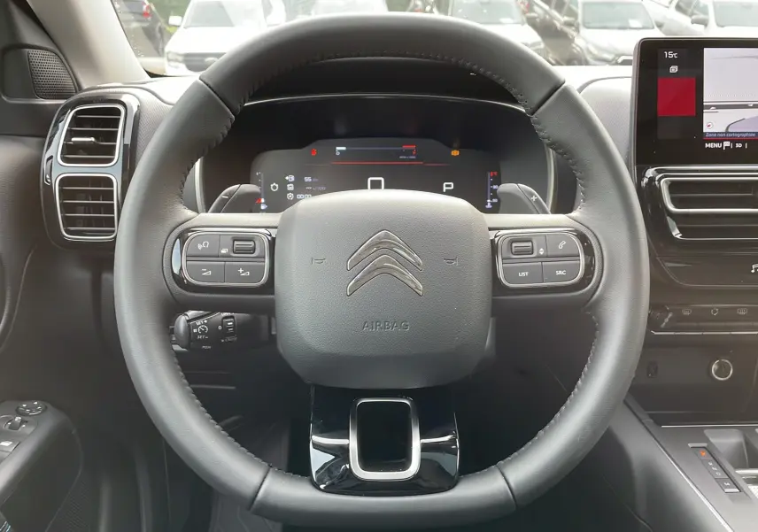 Vue rapprochée du volant noir et du tableau de bord numérique du Citroën C5 Aircross Hybrid 2025 avec commandes intégrées.